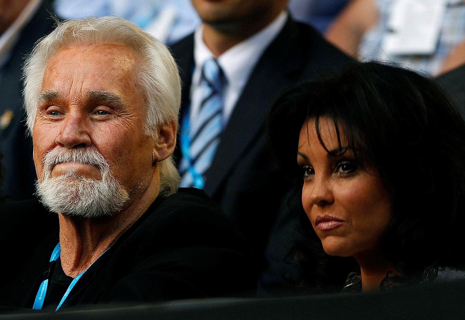 A file photo of Kenny Rogers and his wife Wanda Miller at a sports event in January 2011. Rogers died last Friday and his family will hold a small private service "out of concern for the national Covid-19 emergency".