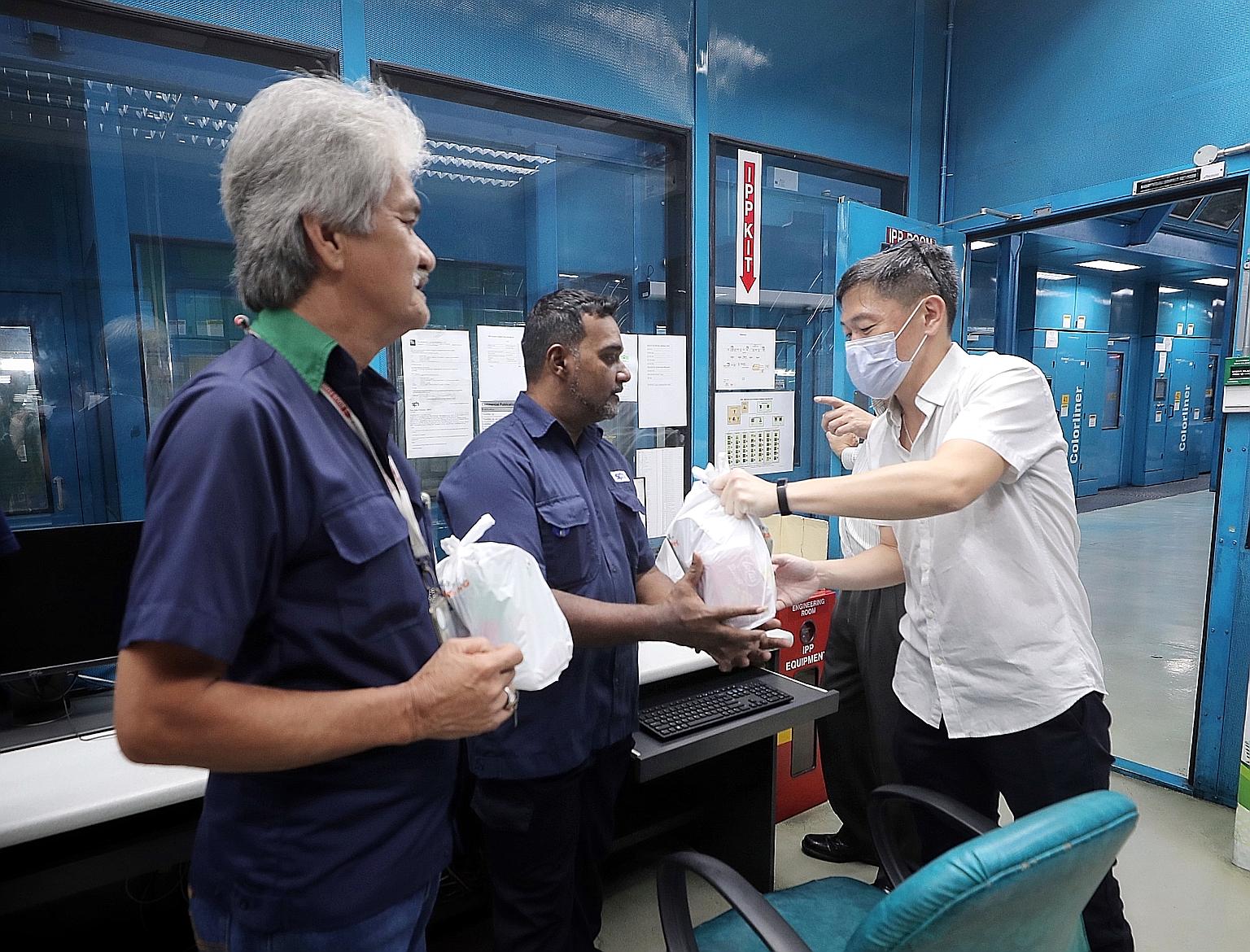 SPH deputy chief executive Anthony Tan giving out a care pack to senior printing staff member Alfred Saranapala at the company's Print Centre yesterday. With them was materials logistics assistant Kamarudin Idrus. Mr Tan was wearing a mask as he is i