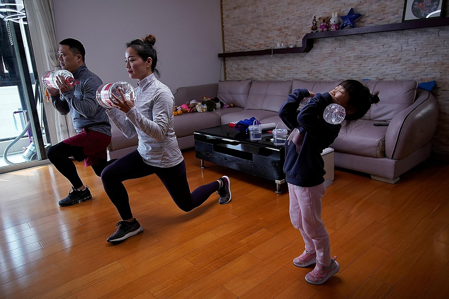The Lin family exercising using filled water bottles as weights as they watch a fitness class online at home in Shanghai last month. There is little reason not to get moving even if you cannot get out. PHOTO: REUTERS