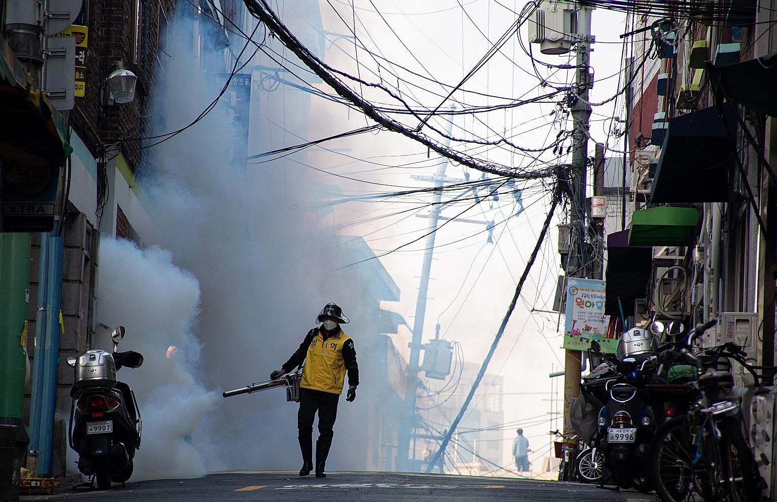 A worker spraying disinfectant as a precaution against further spread of the coronavirus in Seoul, South Korea, last Monday. Cluster infections account for 80 per cent of the country's confirmed cases, the largest cluster being linked to a branch of
