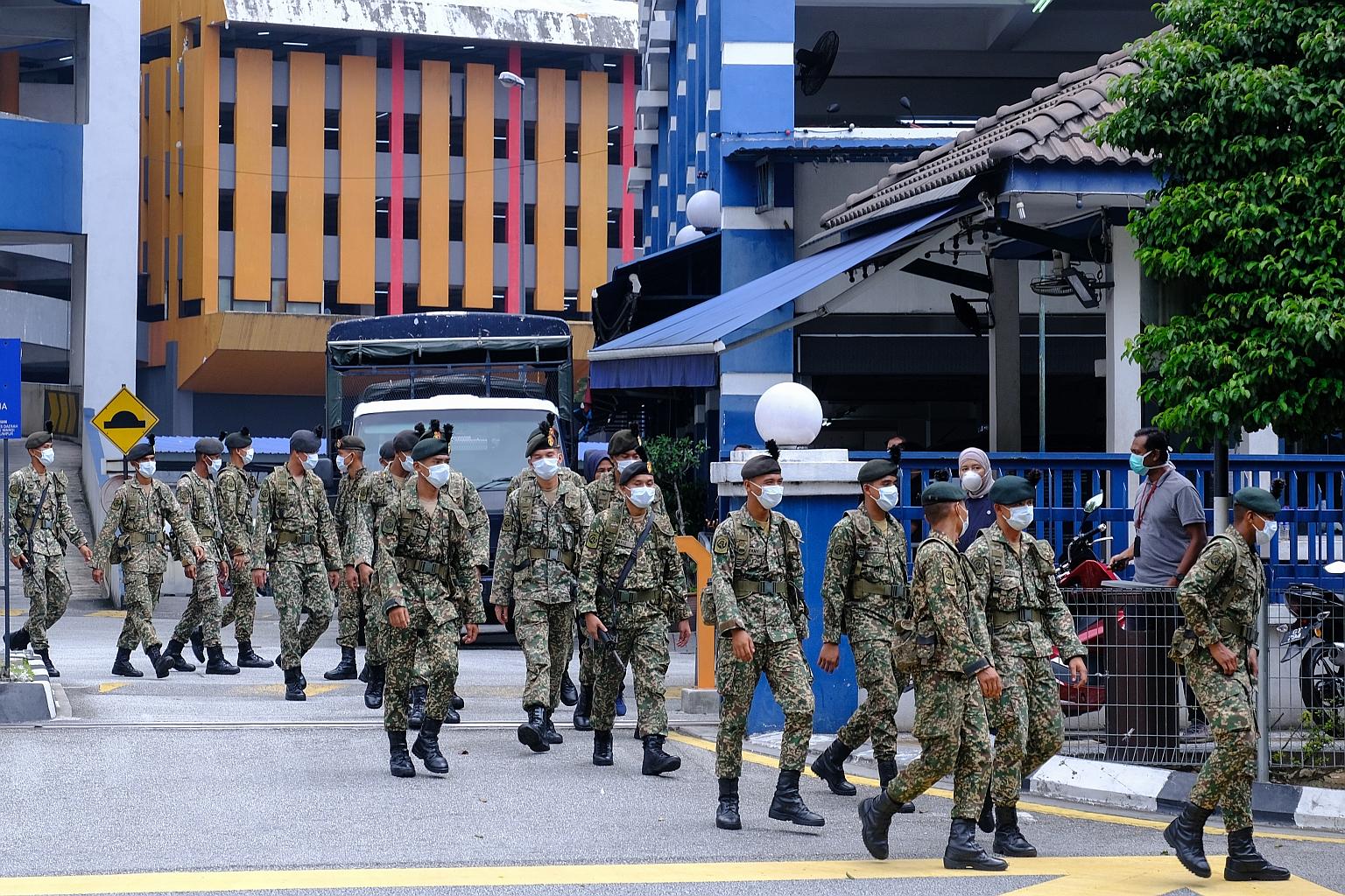 Army personnel leaving a police station in Kuala Lumpur yesterday. The uniformed personnel will be mobilised in cities and rural areas, including at borders, hospitals, supermarkets and wet markets, to ensure people obey the stay-home order.