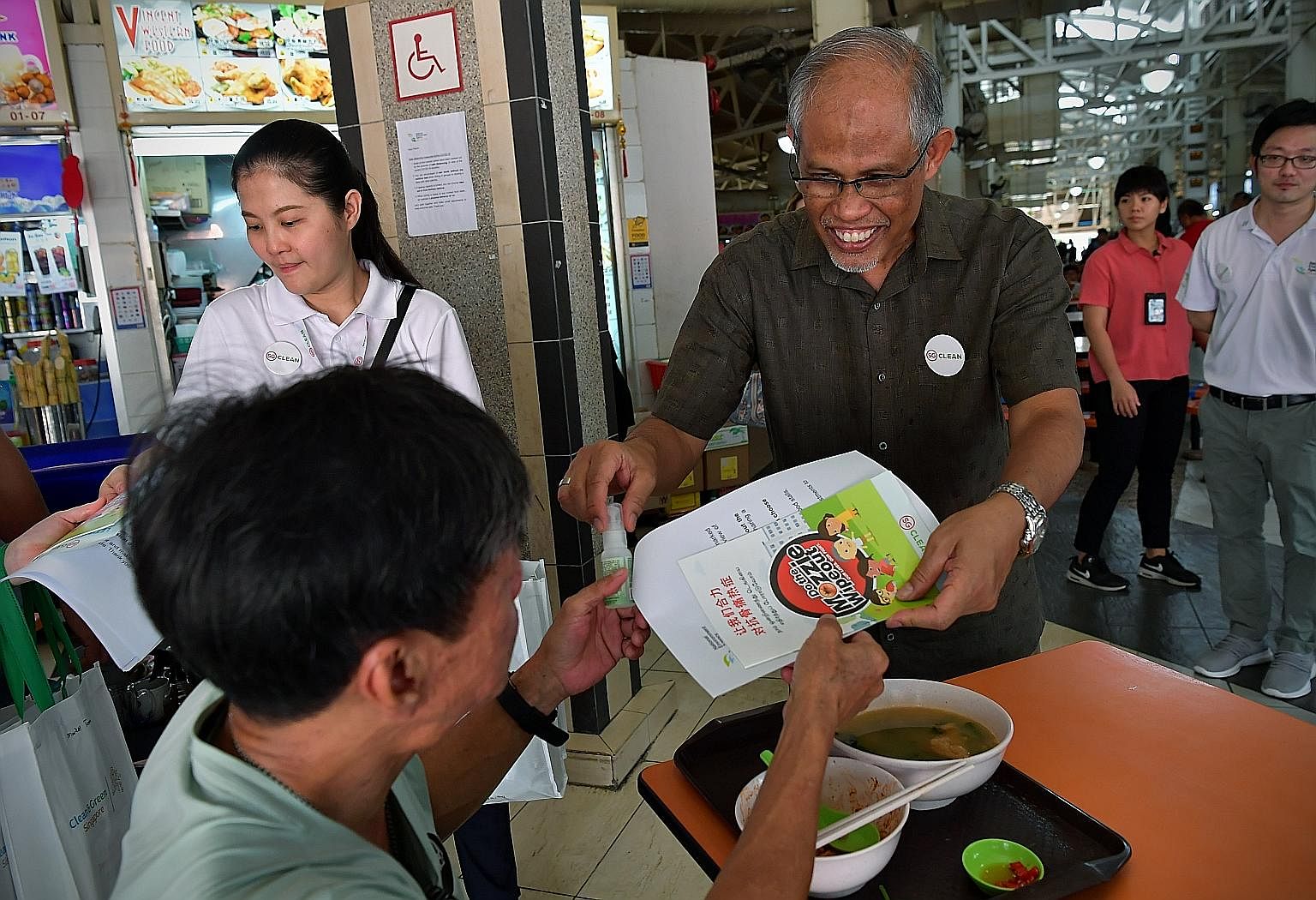 Environment and Water Resources Minister Masagos Zulkifli giving out mosquito repellents and information booklets at the launch of the National Dengue Prevention Campaign in Ang Mo Kio yesterday.