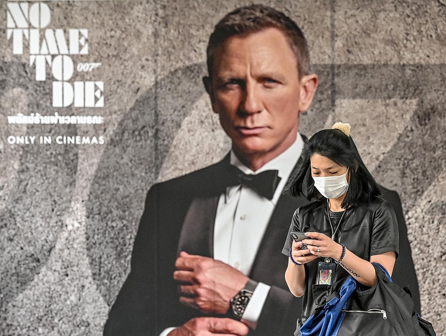 In this photo taken on Feb 28 in Bangkok, a woman walks past a poster for the upcoming James Bond movie No Time To Die, the release of which has been delayed due to the coronavirus pandemic. In A Quiet Place Part II, Emily Blunt (centre) and her fami