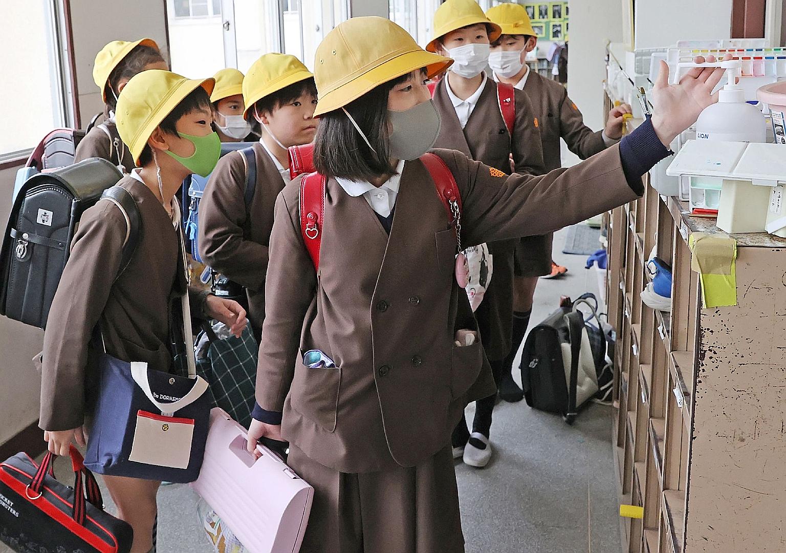 Japanese elementary schoolchildren at an Osaka school disinfecting their hands last month. Most schools in Japan are set to reopen on April 6, after a month-long closure to keep the virus spread in check. PHOTO: AGENCE FRANCE-PRESSE
