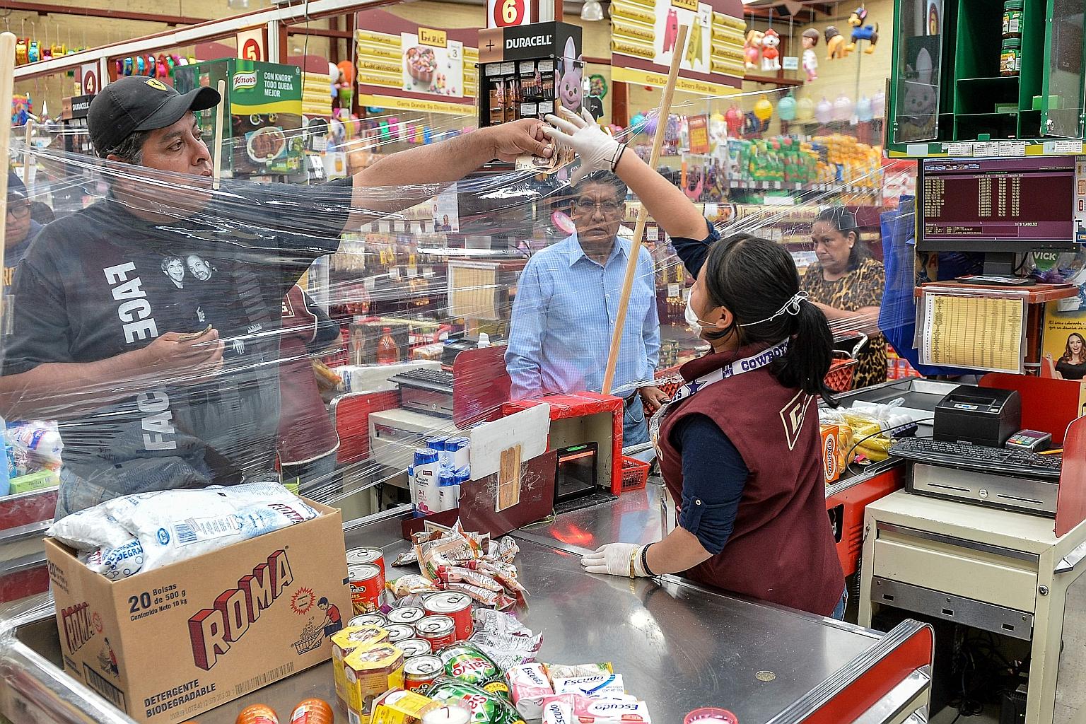 A cashier serving a customer behind a makeshift plastic curtain as a preventive measure against the spread of the coronavirus in Toluca, Mexico, last Friday.