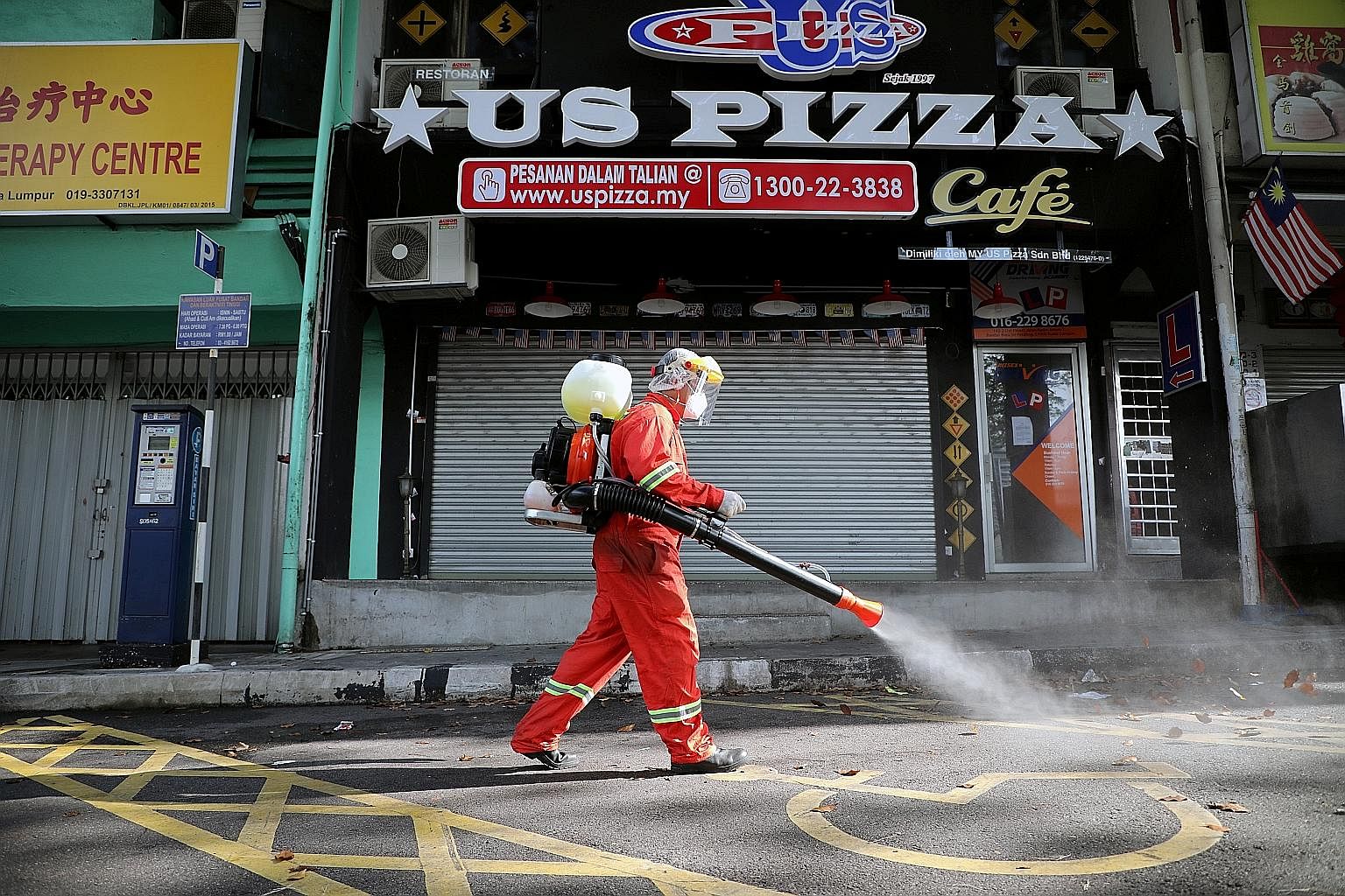 A worker spraying disinfectant on a street in Kuala Lumpur yesterday, while the movement control order is in place due to the coronavirus outbreak. Malaysia on Friday unveiled a RM250 billion (S$83.4 billion) stimulus package to cushion the country's