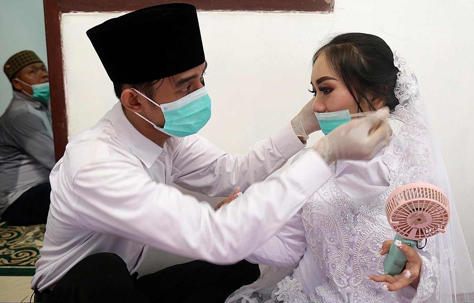 A groom puts a face mask on his bride before their wedding ceremony in Jakarta. The wedding proceeded on Saturday amid concerns about the coronavirus outbreak, which has led the government to consider a lockdown of the capital.