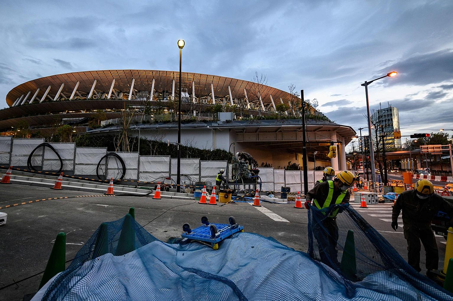 Labourers working at a site near the National Stadium in Tokyo, three days after the historic decision to postpone the 2020 Tokyo Olympics. Despite the delay, organisers are now racing to secure venues for an extra year.
