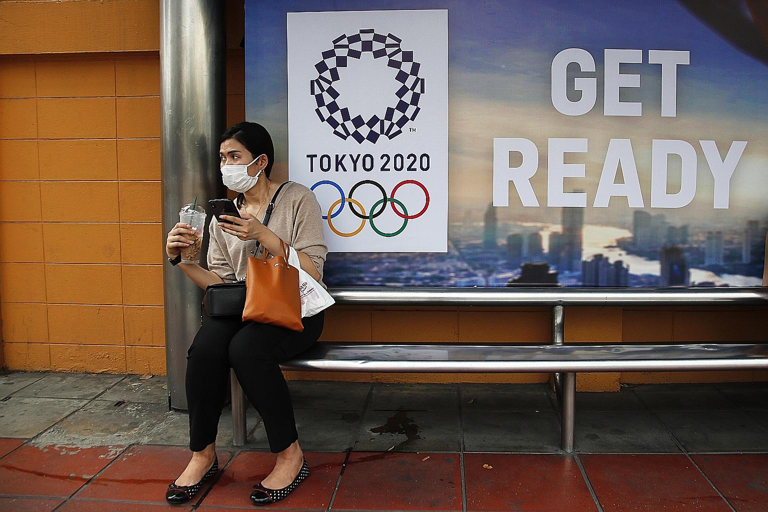 A woman in Bangkok wearing a face mask at a bus stop with a sign promoting the Tokyo 2020 Olympics. The organisers yesterday confirmed the new dates for the Games which were postponed last week due to the coronavirus pandemic.