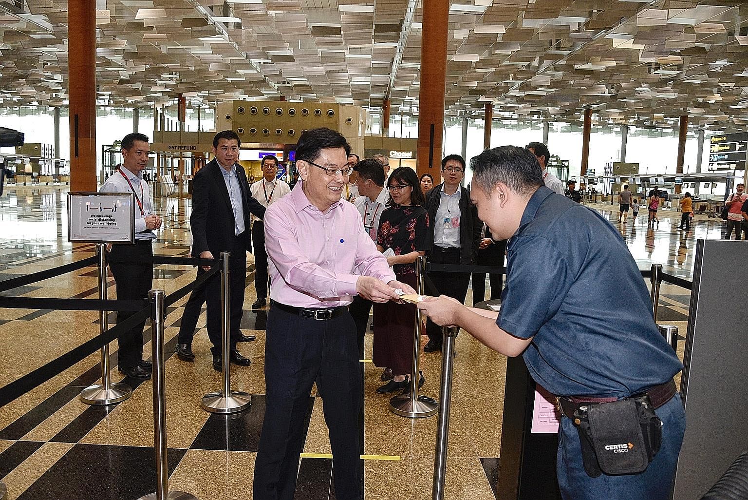 Deputy Prime Minister Heng Swee Keat giving a packet of cookies and an SG United badge from the Civil Aviation Authority of Singapore, packed by Metta alumni youth with special needs, to Certis auxiliary policeman Mohd Nizam at Changi Airport yesterd