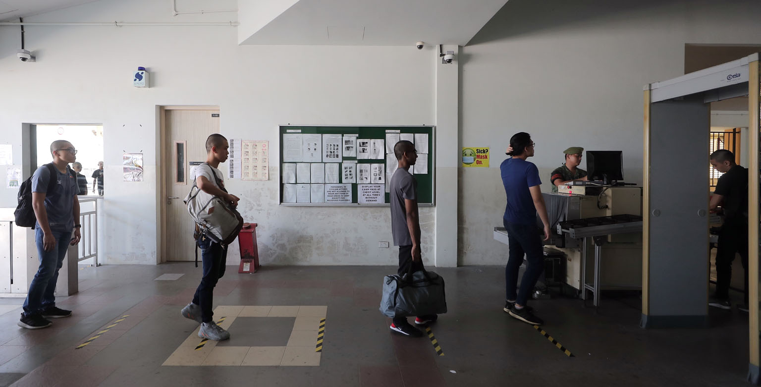 Newly enlisted national servicemen queueing for security checks while practising social distancing at the SAF Ferry Terminal before heading to Pulau Tekong on Wednesday. Defence Minister Ng Eng Hen said yesterday that the SAF has to continue to safeg