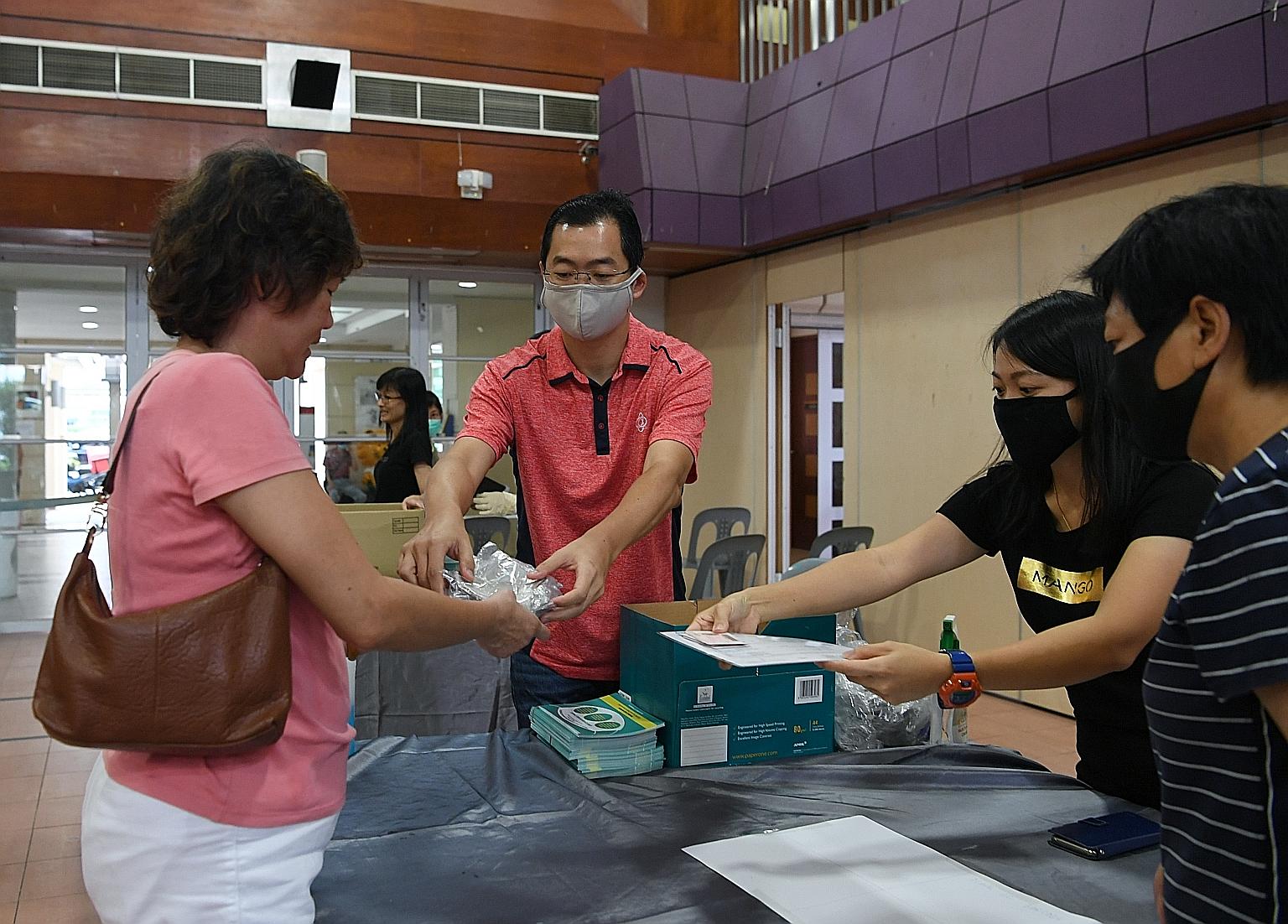 Residents collecting reusable masks at Potong Pasir Community Cub yesterday. At collection points, safe distancing measures were in place for people in the queues, and temperature taking was done before residents could enter the premises. ST PHOTO: K