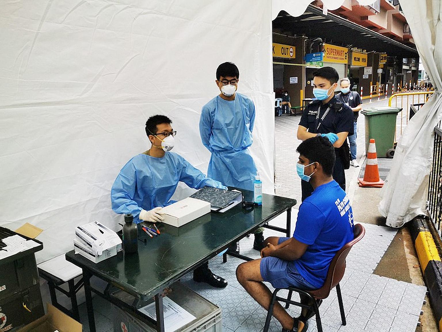 Army Medical Services personnel attending to a foreign worker at Westlite in Toh Guan yesterday.