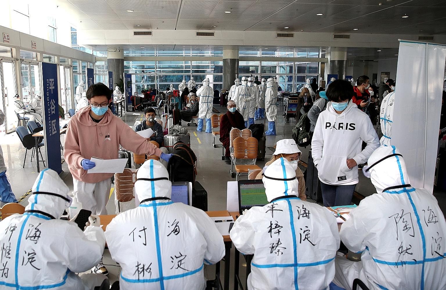 A police officer saluting Chinese medical workers from Shandong province as they prepared to leave Wuhan on Monday. There are now fears, however, of a second wave of infection in China from imported cases. PHOTO: EPA-EFE People registering at a trans