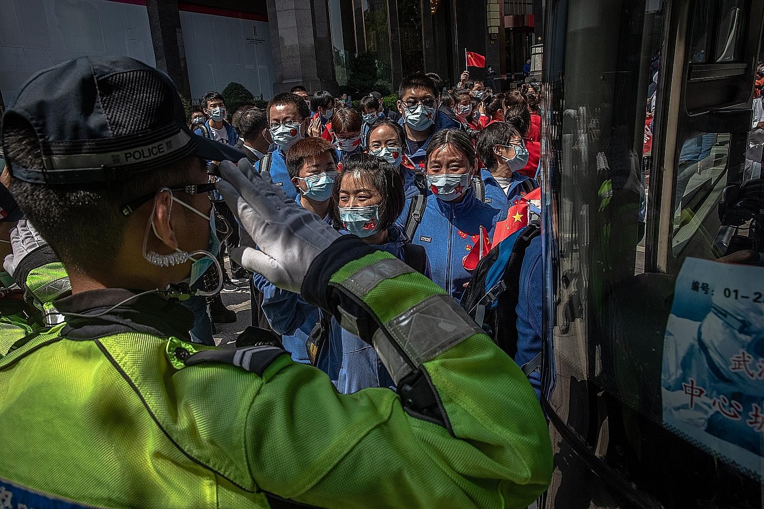 A police officer saluting Chinese medical workers from Shandong province as they prepared to leave Wuhan on Monday. There are now fears, however, of a second wave of infection in China from imported cases. PHOTO: EPA-EFE People registering at a trans