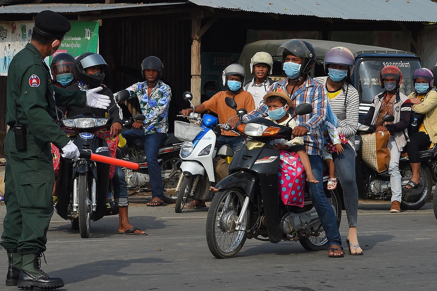 Police stopping motorists yesterday at a checkpoint set up at the border between Phnom Penh and the neighbouring Kandal province in Cambodia. The government on Thursday banned travel between provinces and districts for a week to curb the spread of th