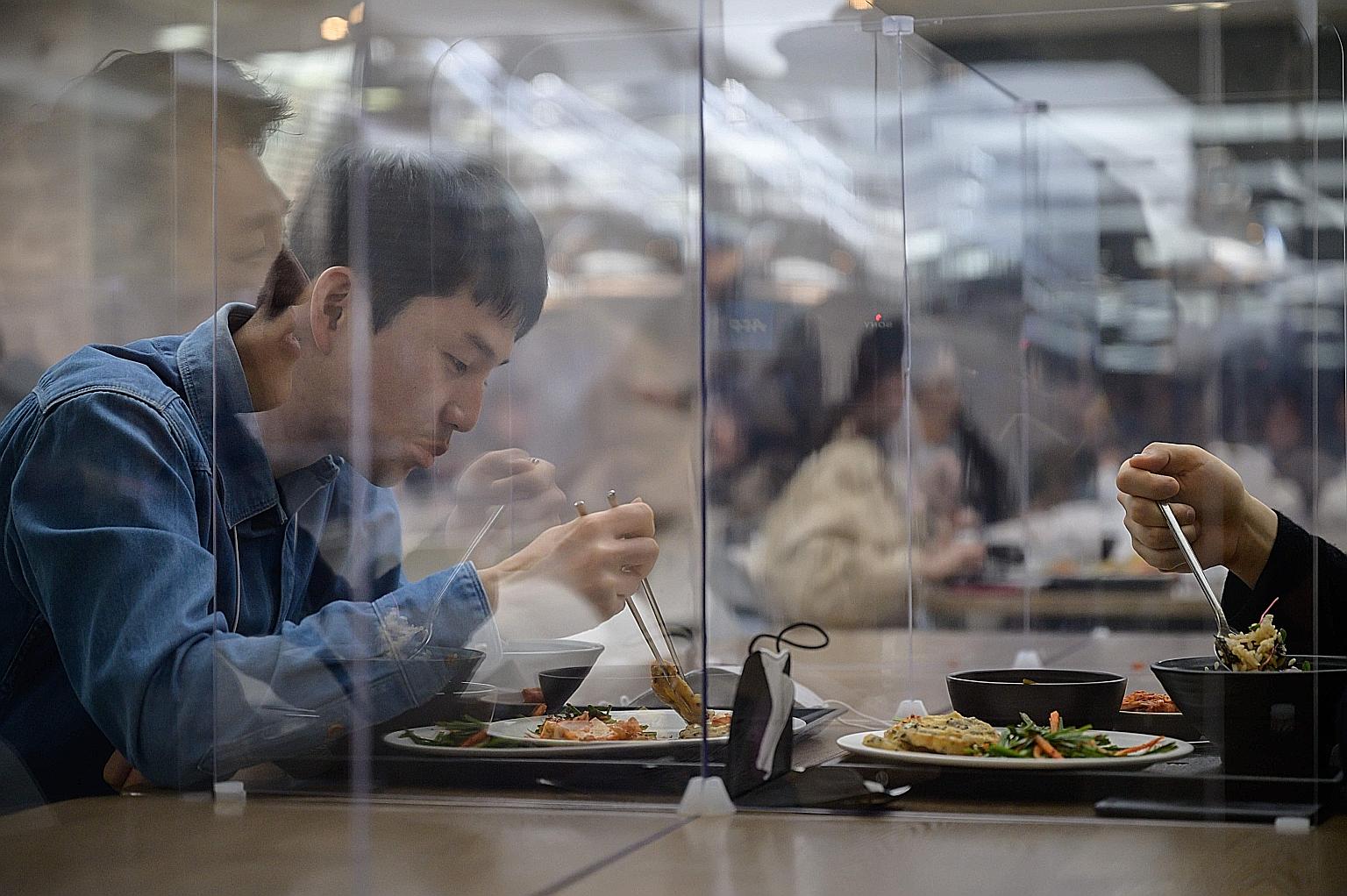 People in South Korea last Thursday eating behind protective screens that aim to help prevent the spread of the coronavirus.