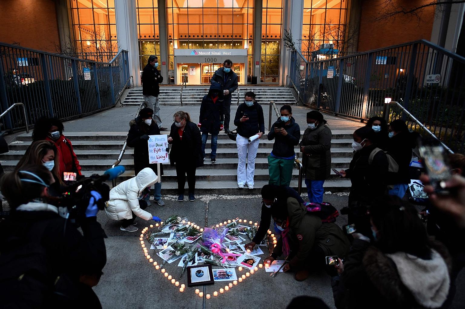 Healthcare workers lighting candles as they mourned their colleagues who died during the outbreak of the coronavirus during a demonstration at Mount Sinai Hospital in Manhattan on Friday. New US government data shows infections will spike during the 