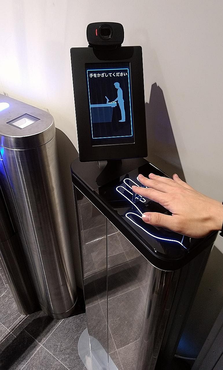 A customer trying out a palm reader installed at the entrance of a trial convenience store concept at Fujitsu's office in Kawasaki. This replaces checkout registers by using a non-contact, multi-biometric authentication system that enables identifica