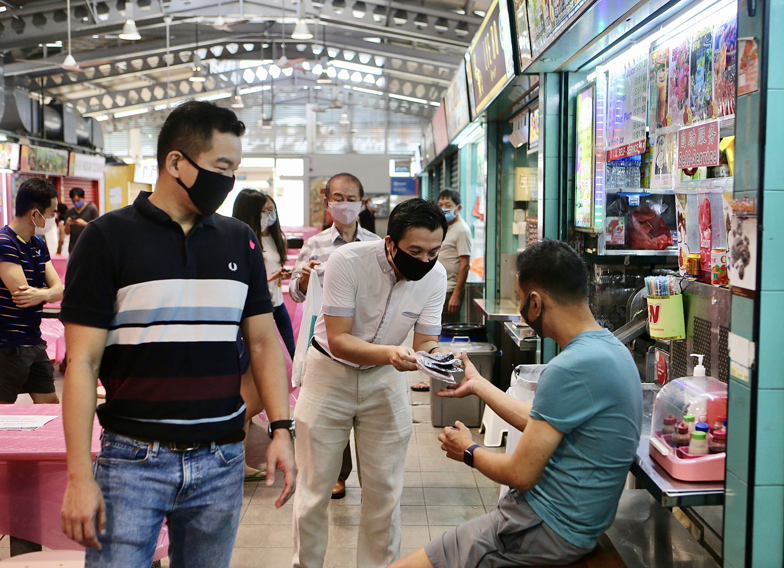 Tanjong Pagar GRC MP Chia Shi-Lu distributing reusable face masks to a hawker at Alexandra Village Food Centre on Sunday. With him is Colonel Eric Chua (in striped T-shirt).