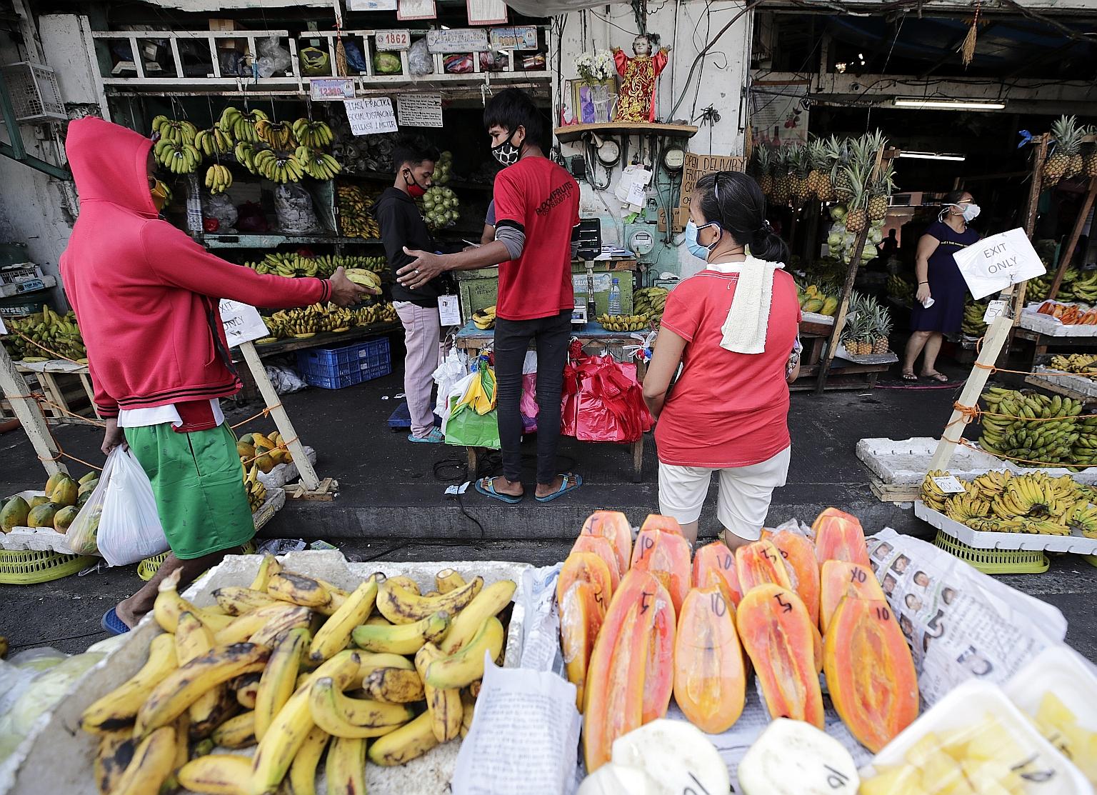 Fruit sellers and customers with face masks on in Manila. To counter the coronavirus outbreak, Philippine President Rodrigo Duterte has extended curbs on movement, which have idled the economy and cost over a million jobs. PHOTO: EPA-EFE