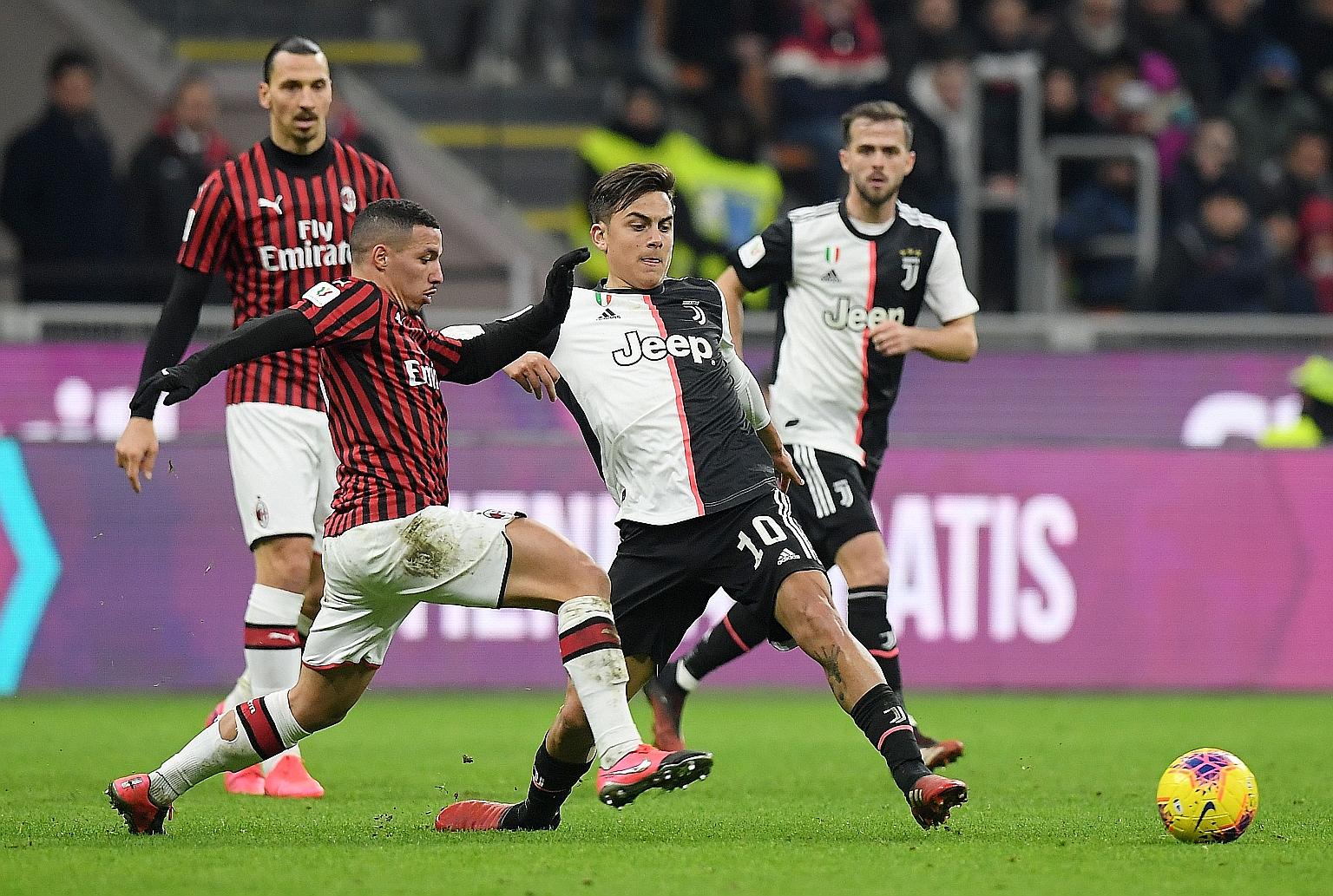 Juventus attacker Paulo Dybala fending off AC Milan's Ismael Bennacer during an Italian Cup match in February. Dybala, one of the Juventus players who tested positive for the coronavirus, will have to prove his fitness if the Serie A resumes. PHOTO: 