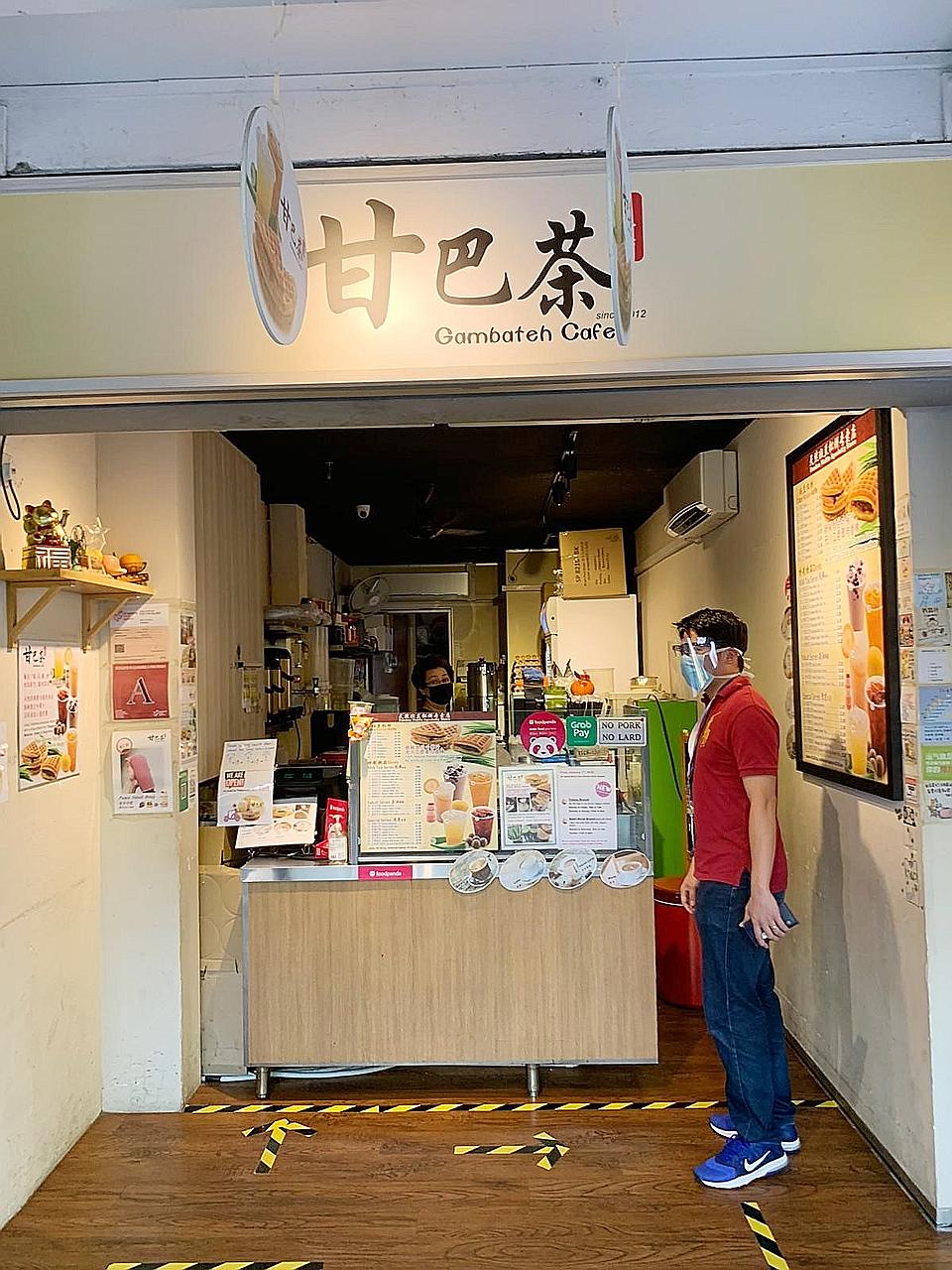 Mr Ashley Ng, who volunteers as a safe distancing ambassador, advising a cafe owner on how to maintain safe distancing measures.