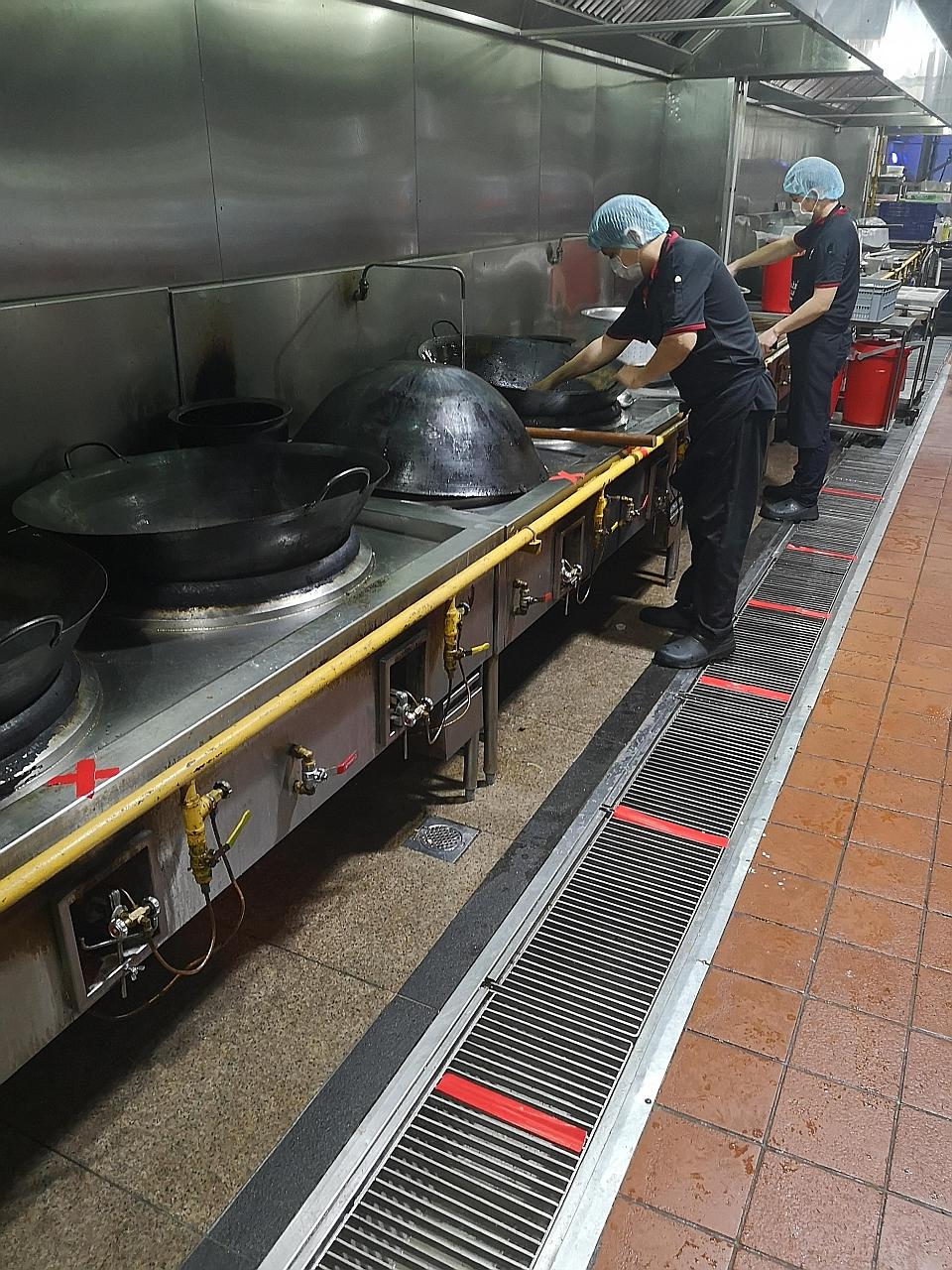 Employees of Elsie's Kitchen at its central kitchen in Jurong West adhering to social distancing measures while preparing food for delivery. The caterer has ramped up its delivery operations by sending rice sets to healthcare workers and the foreign