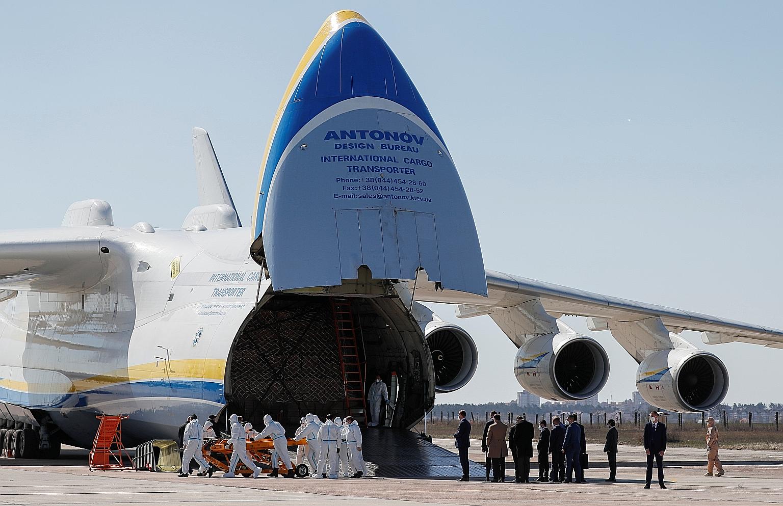 Officials, including Ukraine's President Volodymyr Zelensky, watching as medical supplies from China are being unloaded from a cargo plane at an airfield outside Kiev yesterday. China has donated more money to the WHO to support the fight against Cov