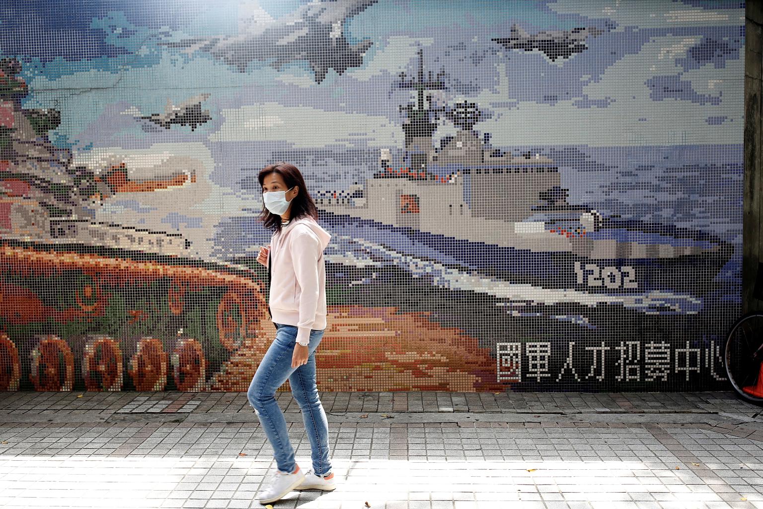 A masked woman walking past a Ministry of National Defence recruitment poster in Taipei, as the authorities mull over anti-virus steps.