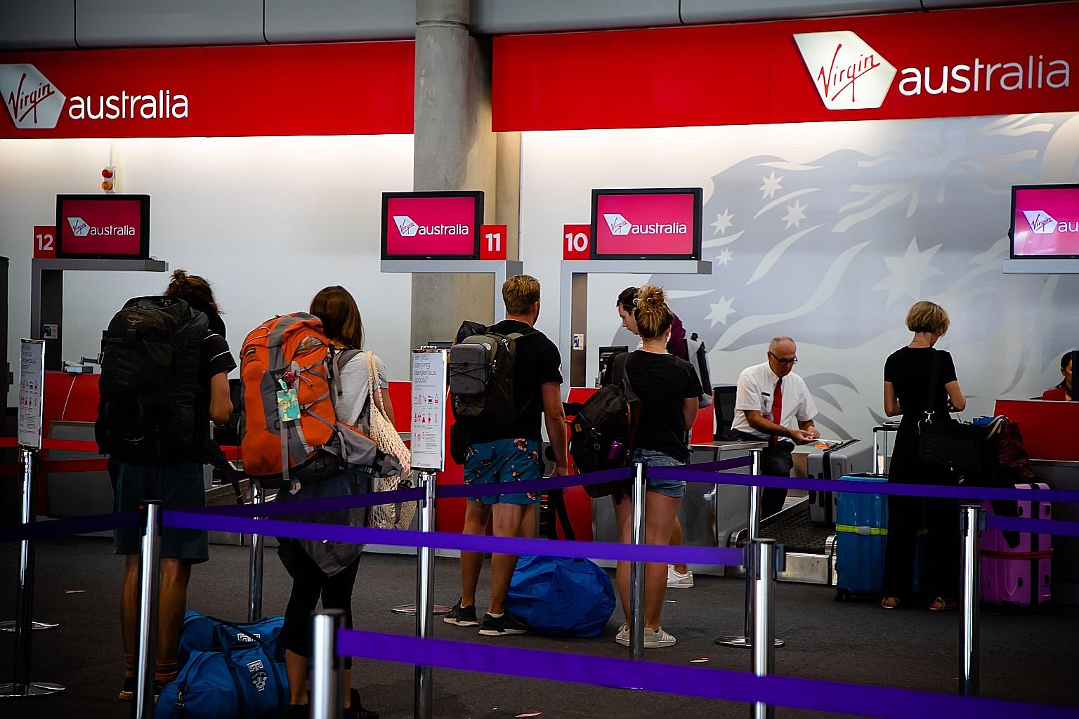 Passengers checking in at the Virgin Australia counter in Brisbane's domestic terminal. Virgin Australia on Tuesday succumbed to third-party led restructuring that could lead to a sale.