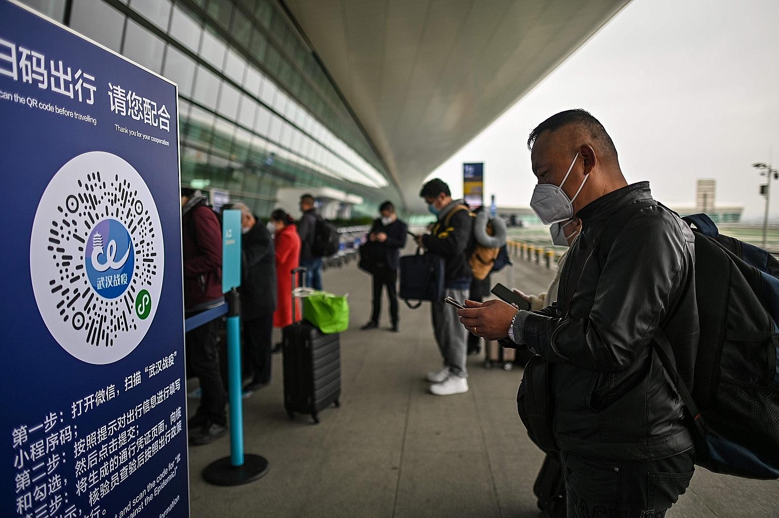 A passenger wearing a mask preparing to scan a Wuhan city health QR code before entering Tianhe Airport in Wuhan, Hubei province, on April 11. Citizens are required to register for a health code - applets developed by the government to track whether 