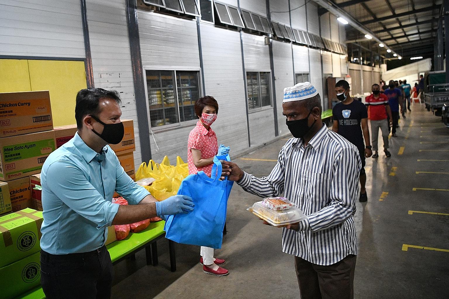 Minister of State for Manpower Zaqy Mohamad and Senior Parliamentary Secretary for Manpower and Mayor of South West District Low Yen Ling handing out meals to Muslim migrant workers early yesterday morning at the PPT Lodge 1A in Seletar North Link. Y