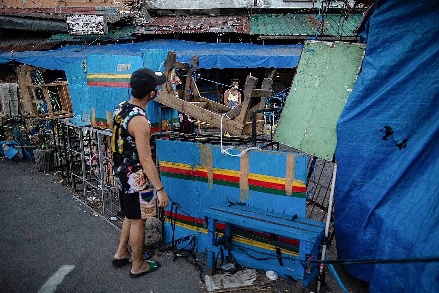 THE PHILIPPINES Men with face masks talking across makeshift barriers placed on a street yesterday amid the lockdown in Manila. PHOTO: REUTERS AUSTRALIA Eight-year-old twins Oriana (far left) and Rafaela Ikladious holding pictures that they drew duri