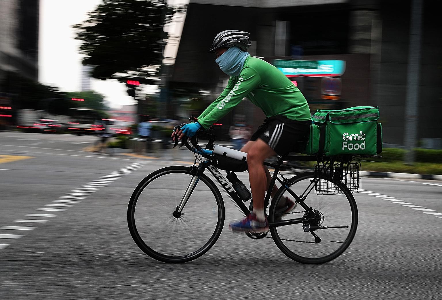 A GrabFood delivery partner in the city area earlier this month. With people staying in and more ordering food, it is not difficult for riders to make about 20 trips a day.