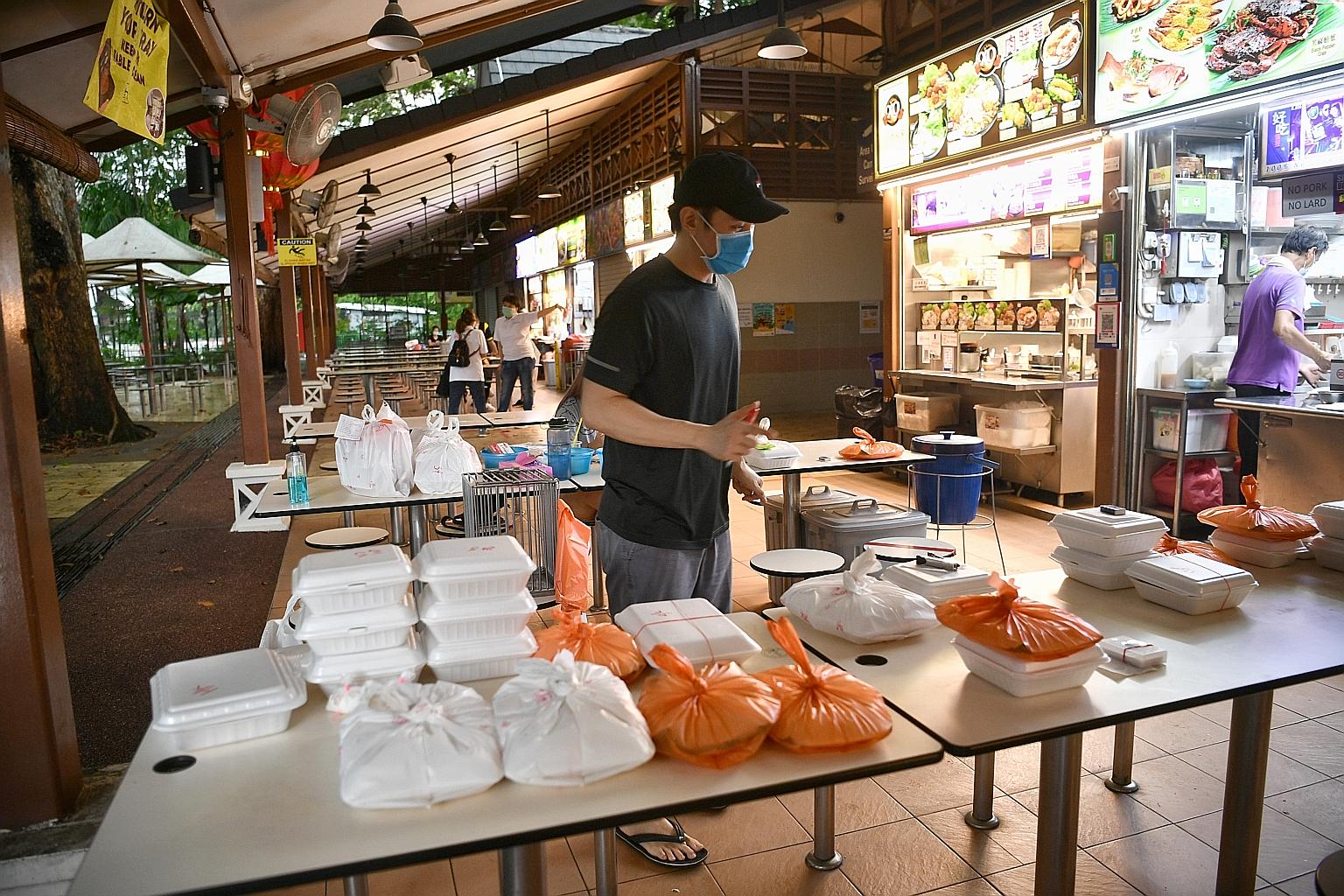Mr Kelvin Foo, the owner of Hai Yan BBQ Seafood, managing delivery orders on Friday. The stall, at Newton Food Centre, uses four tables to split up the deliveries bound for different locations. This way, delivery personnel are kept at least 1m apart 