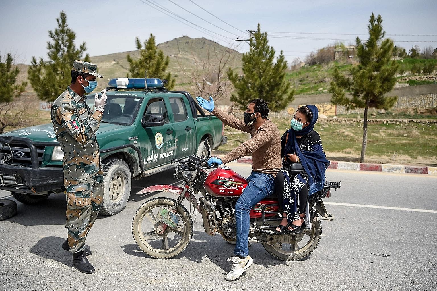An Afghan security officer stopping motorists at a checkpoint in Kabul on April 8, during a government-imposed lockdown as a preventive measure against Covid-19. The virus may have brought much of the world to a standstill, but it has not ended confl