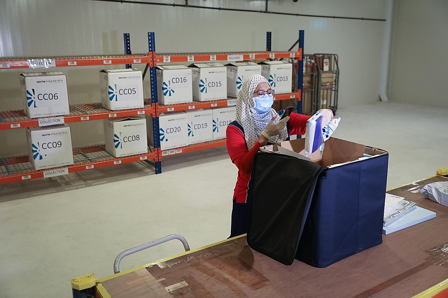 Speedpost courier Ismadiana Samsudin, 37, collecting a cold-chain box for delivery of medications that require refrigeration at SingPost's regional e-commerce logistics hub in Tampines last Friday.