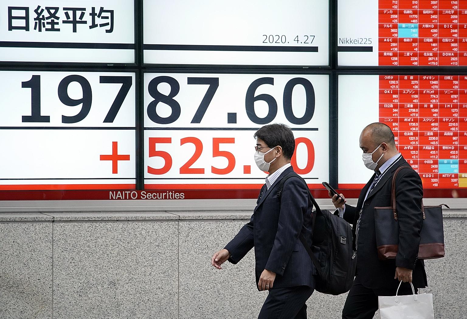 A stock market indicator board in Tokyo yesterday. The Bank of Japan said it would shift to unlimited government bond buying and more than double its capacity to purchase corporate bonds and commercial papers.