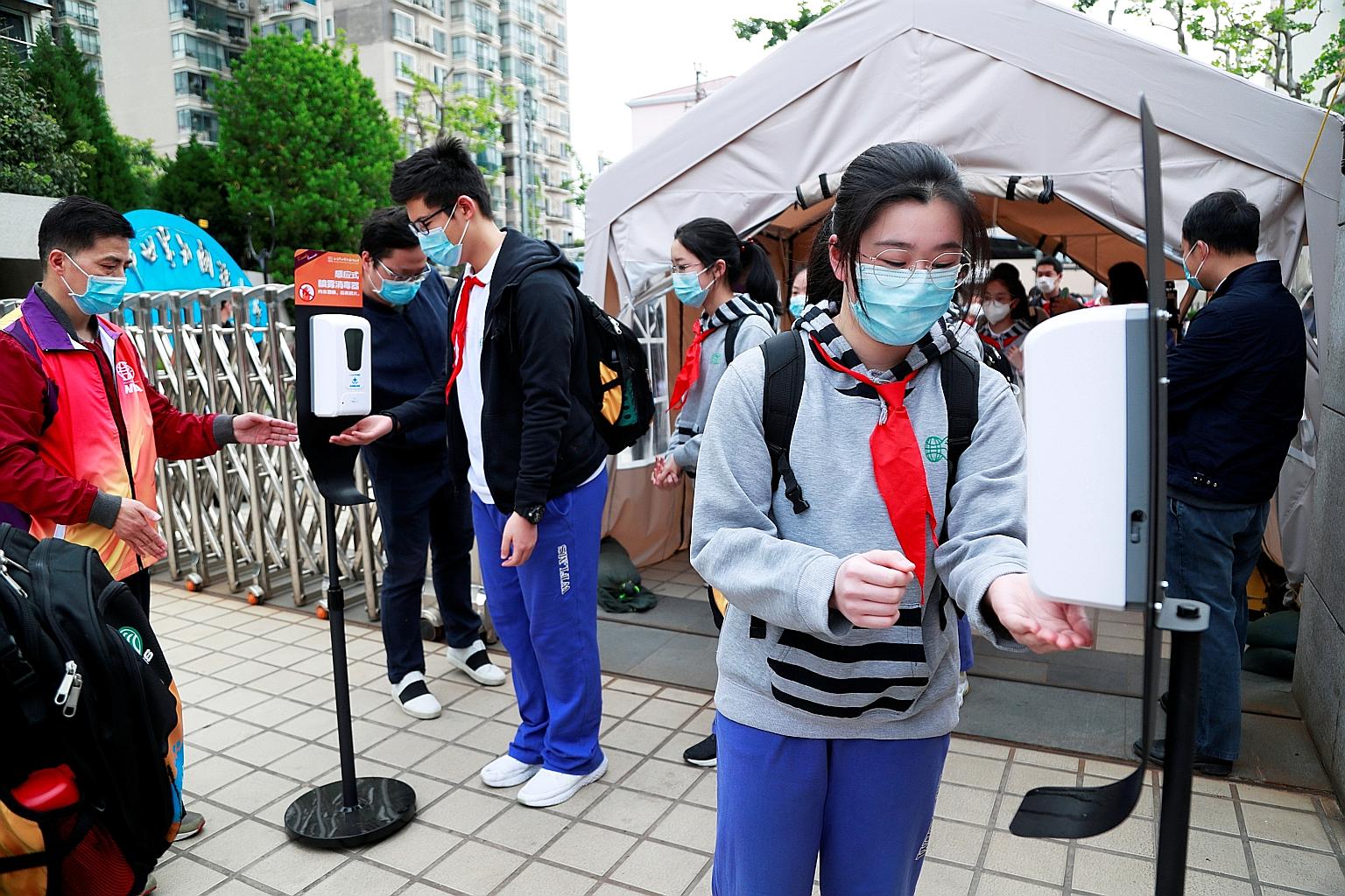 Students wearing face masks using hand sanitisers at an entrance to a school in Shanghai yesterday, as the Chinese city allowed final-year senior and middle high school students to return to campus. But strict anti-virus measures must still be follow