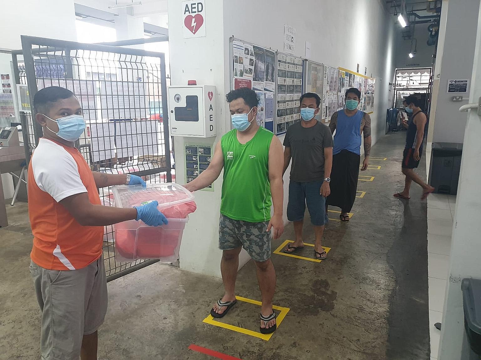 Safe distancing markers in place at local construction firm Woh Hup's dormitory in Joo Koon to ensure that food collection can be done safely. Workers at the Joo Koon dormitory keeping their distance from one another while waiting to have their tempe
