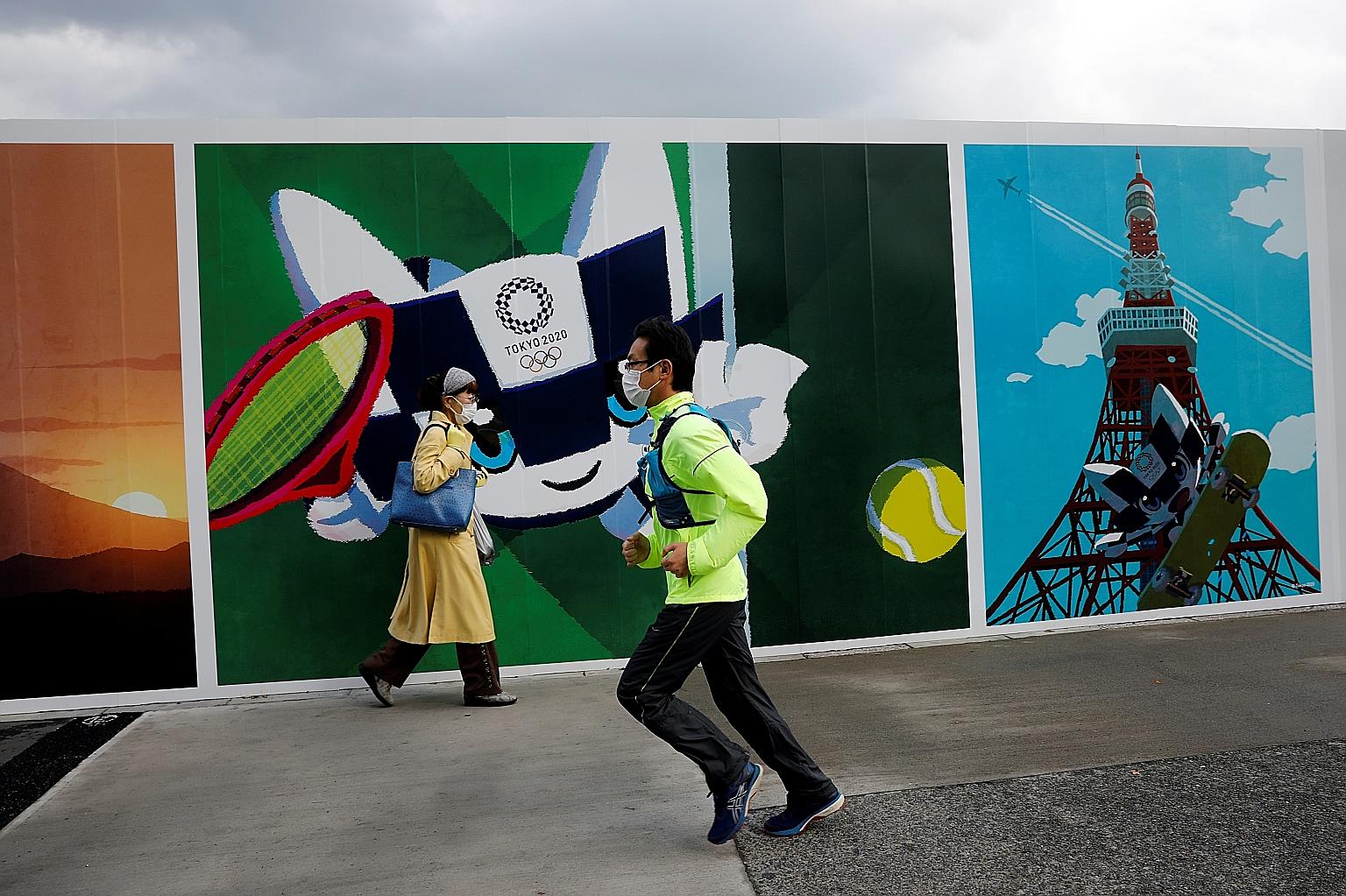 A man in Tokyo wearing a protective face mask and jogging past a wall with the Tokyo 2020 mascot on Tuesday. The Olympics have been rescheduled to July 23-Aug 8 next year owing to the coronavirus pandemic. PHOTO: REUTERS