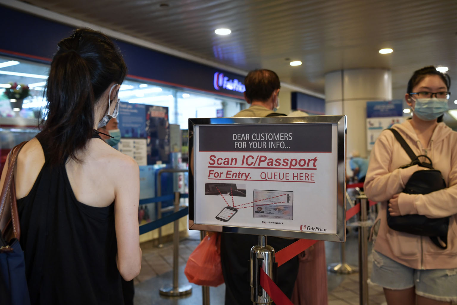 Above: A sign outside Nex shopping mall on Tuesday telling people entering and exiting the mall to scan a QR code and enter their details for contact tracing purposes. Left: A notice asking customers to scan their NRIC or passport for entry into a Fa