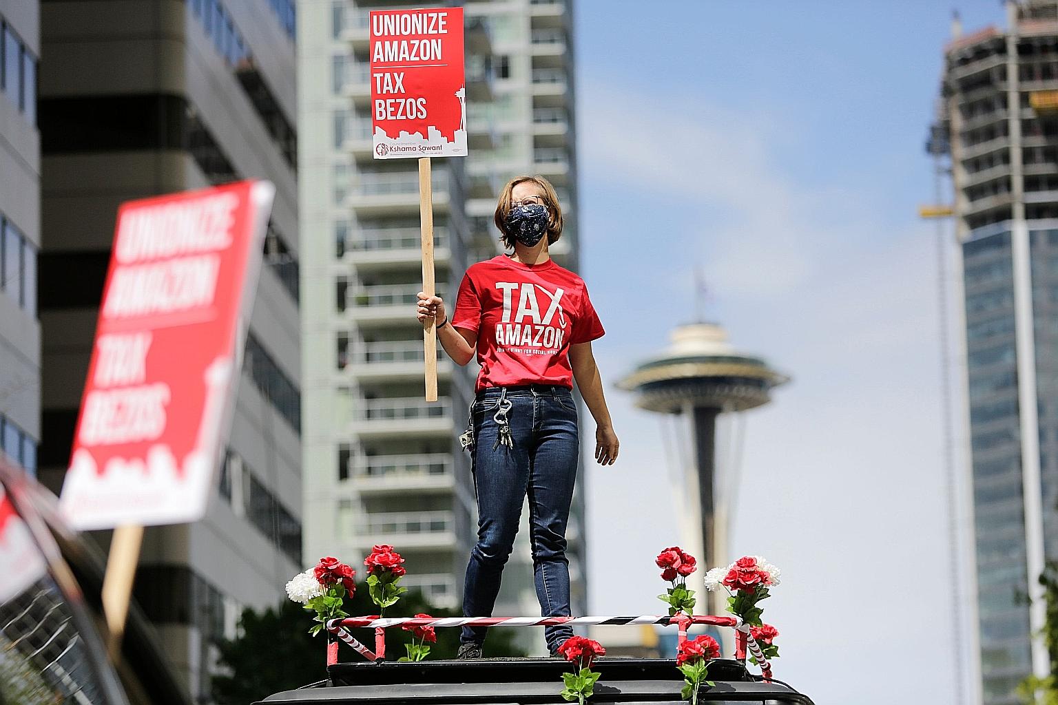 A protester standing on her car, holding up a sign referring to Amazon chief executive Jeff Bezos and blocking traffic as part of a "car caravan" protest on Friday in Seattle, Washington, to demand that the city's largest businesses, including Amazon
