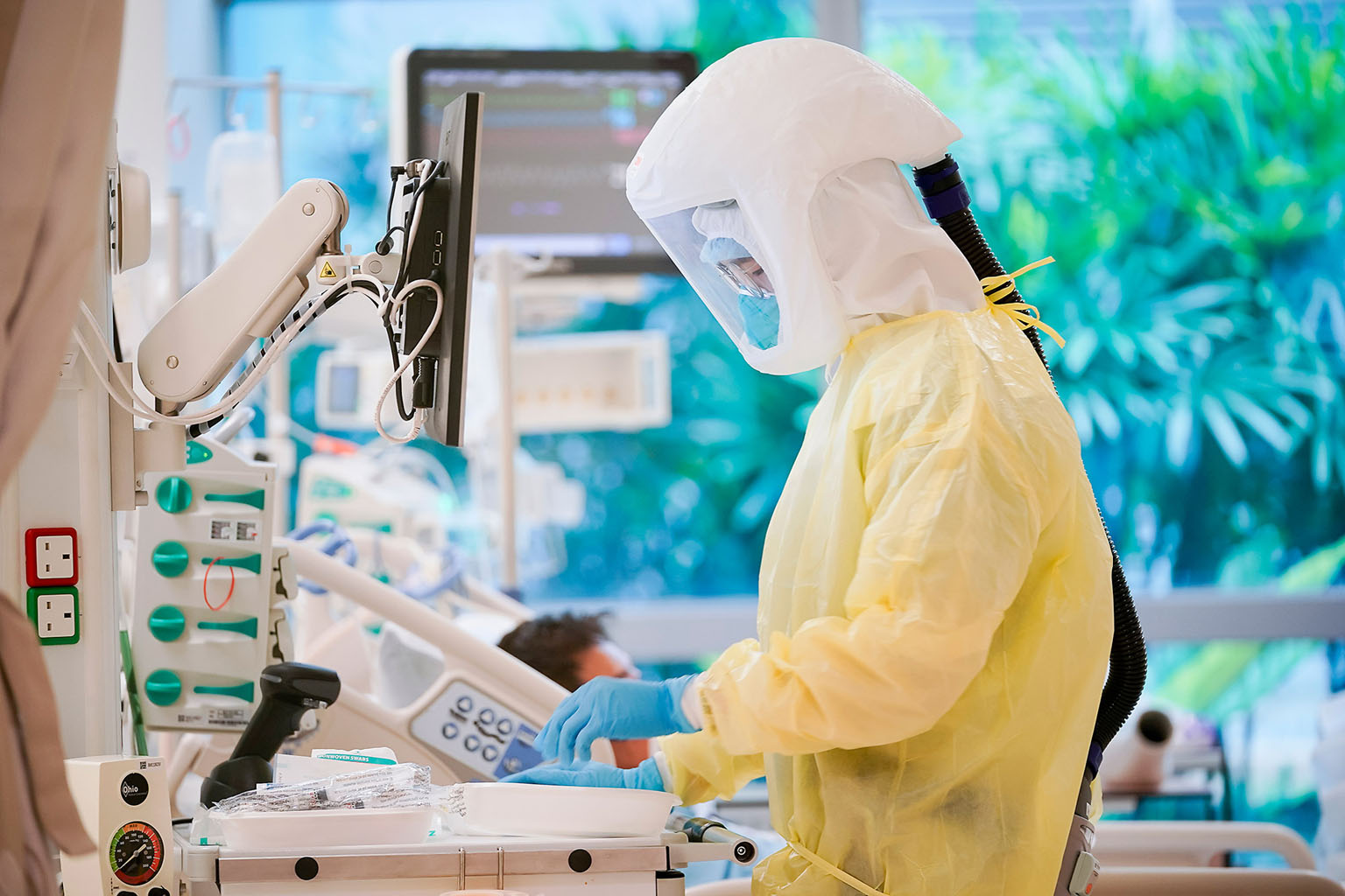 Senior staff nurse Wee Zhen Chian monitoring Mr Tan's condition at Ng Teng Fong General Hospital. Mrs Tan looking at her husband from outside his ICU room before being transferred from her own ICU room to a general ward by staff nurse Ma Jing. Throug