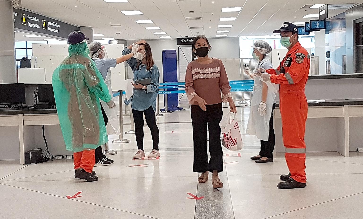 ST reporter Tan Hui Yee on an almost empty flight from the Thai capital Bangkok to the north-eastern province of Ubon Ratchathani. From left: An attendant on the one-hour flight from Bangkok to Ubon Ratchathani wearing disposable plastic overalls on 
