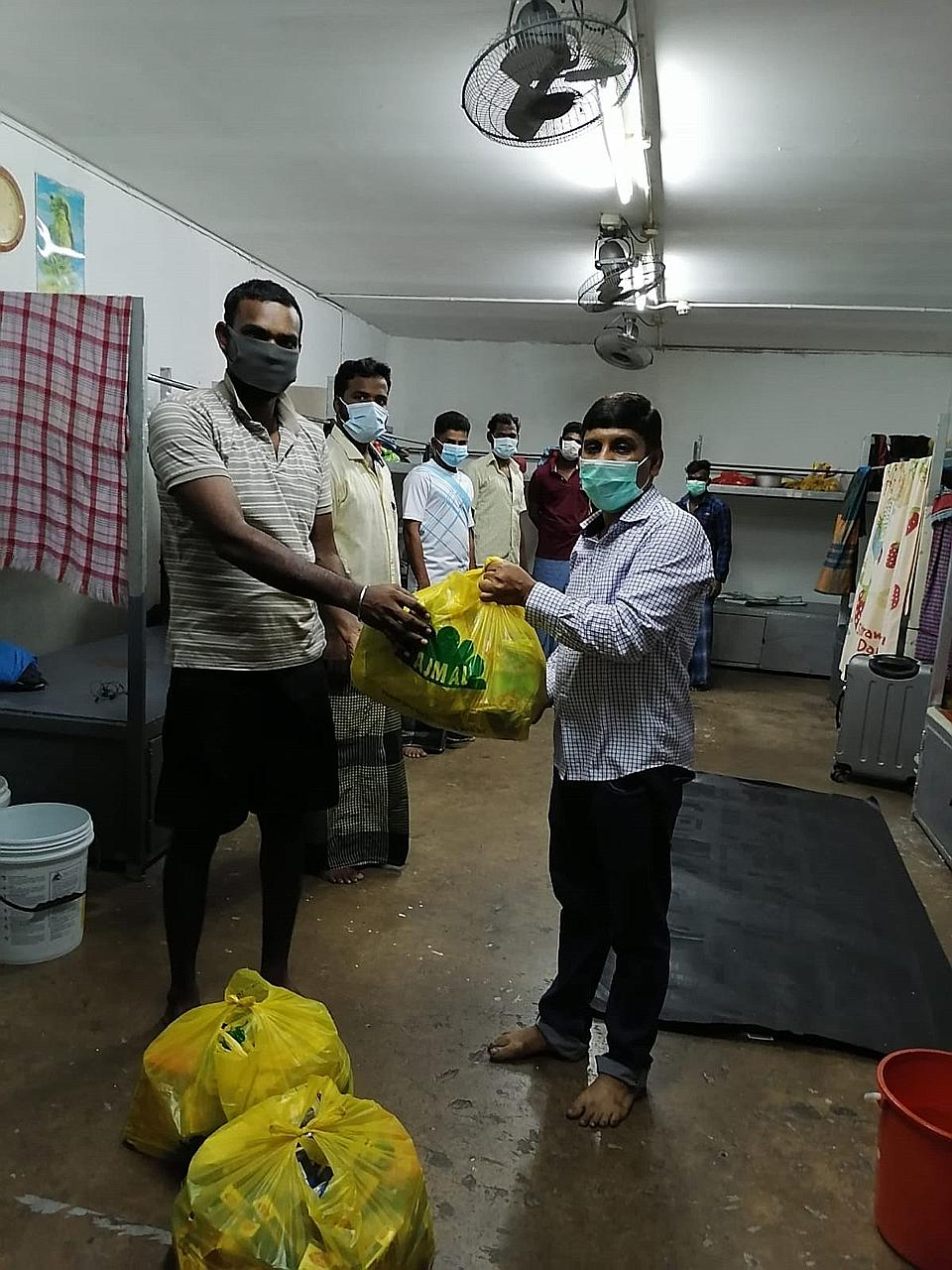 Workers at the 53 Sungei Kadut Loop dormitory with the essential items they received from OCBC Bank. Since last Monday, the bank has been providing food, necessities, personal protective gear and cleaning equipment to migrant workers in isolation.