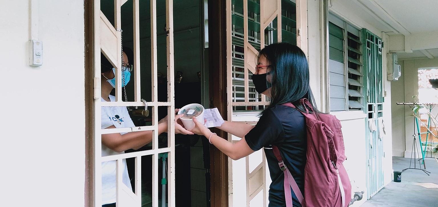 Miss Lim Si Hui, senior lead of outreach and partnerships at Glyph, delivering a meal from Knead to Eat to a resident in Bukit Merah.