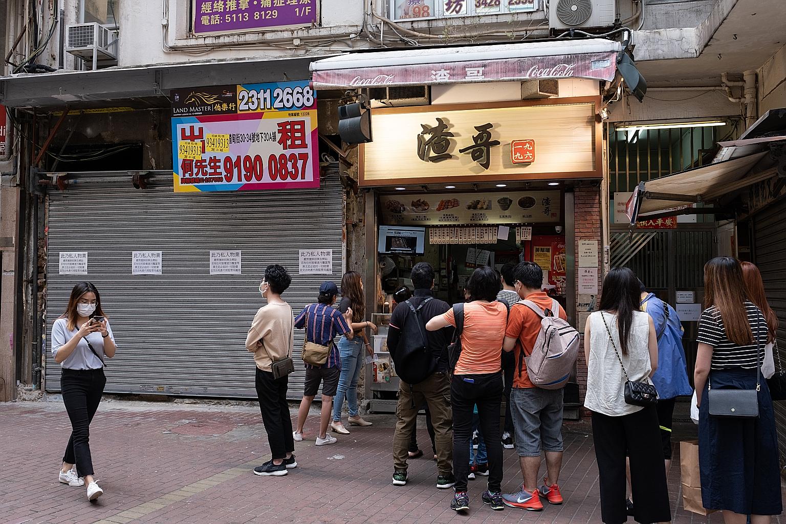 Customers lining up at a food outlet, while another one remains shut, in Hong Kong. Private consumption expenditure fell 10.2 per cent in the first quarter from a year earlier as social distancing measures brought consumption-related activities to a