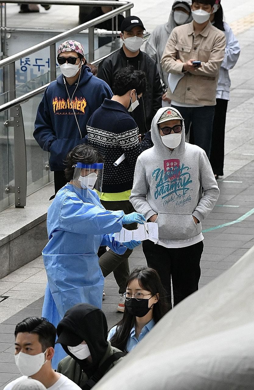 A medical worker in protective gear guiding people towards a Covid-19 test centre in the nightlife district of Itaewon in Seoul, South Korea, yesterday.